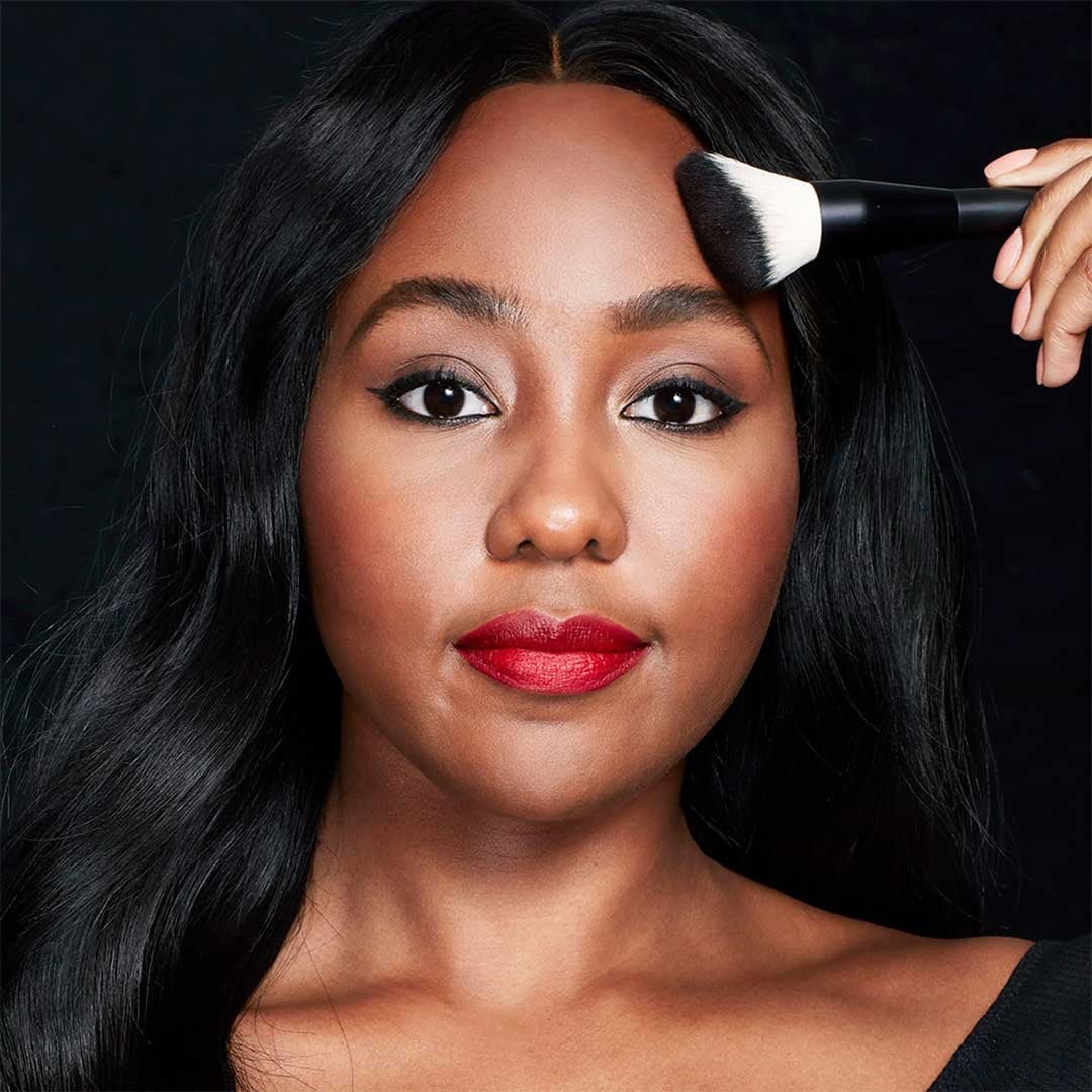Model applying Lasting Fix Setting and Perfecting Loose Powder by Maybelline to forehead.