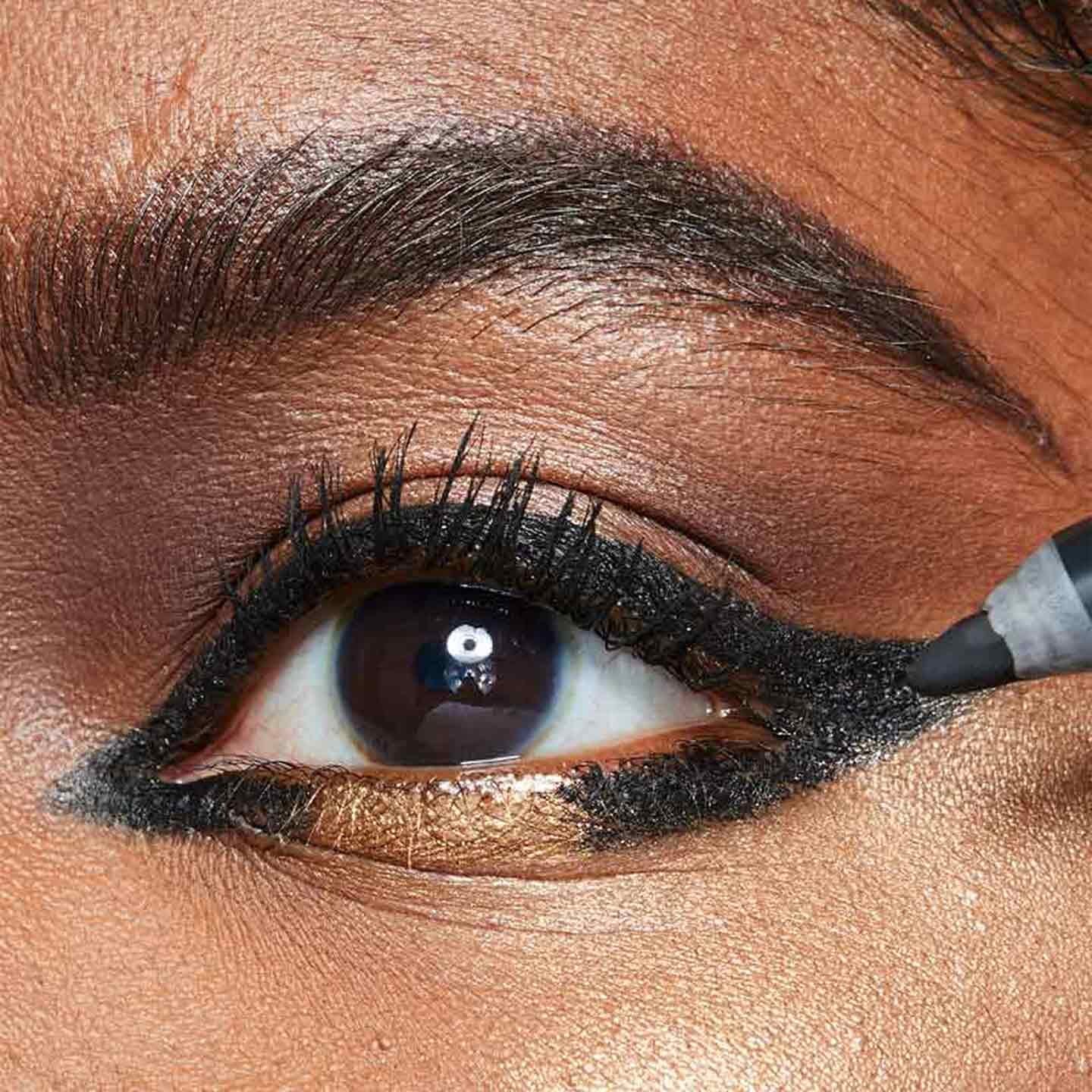 Model creates an open winged eyeliner look with black liner by Maybelline.
